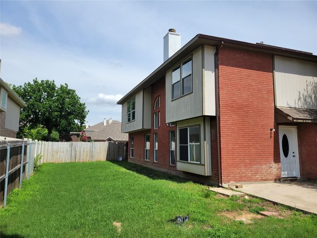 Back of property featuring a fenced backyard, a chimney, brick siding, and a patio | Image 4