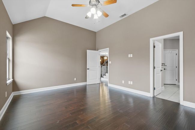 Unfurnished bedroom featuring high vaulted ceiling, wood finished floors, baseboards, and a ceiling fan | Image 18