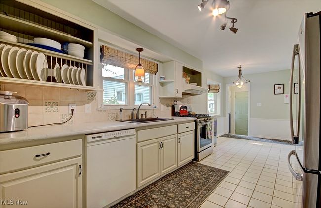 Kitchen featuring appliances with stainless steel finishes, open shelves, tasteful backsplash, light tile patterned floors, and light countertops | Image 15