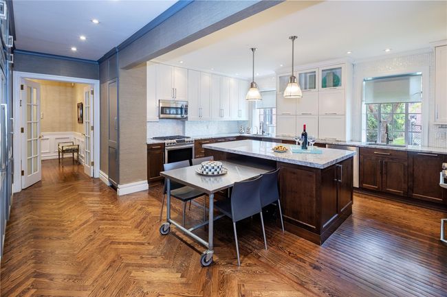 Kitchen featuring appliances with stainless steel finishes, a center island, white cabinets, ornamental molding, and healthy amount of natural light | Image 5