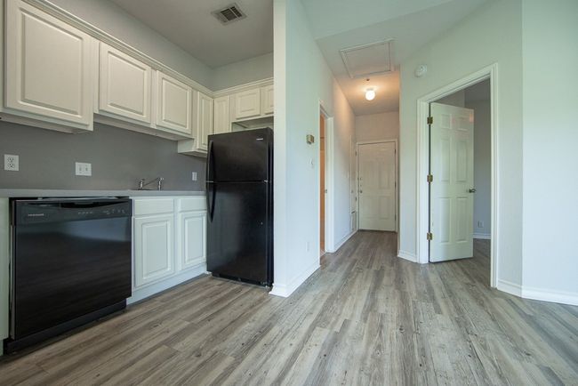 Kitchen with black appliances, light wood-style floors, white cabinetry, and light countertops | Image 11
