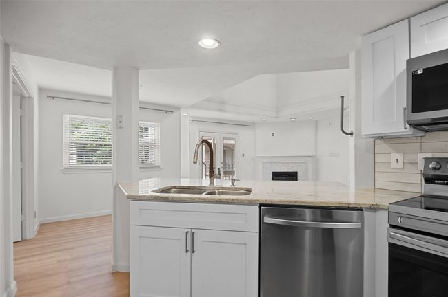 Kitchen featuring appliances with stainless steel finishes, a sink, light stone counters, light wood-style floors, and white cabinets | Image 10
