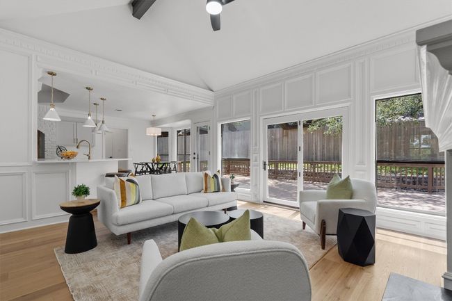 Living area with a decorative wall, light wood-type flooring, beamed ceiling, ceiling fan, and high vaulted ceiling | Image 4