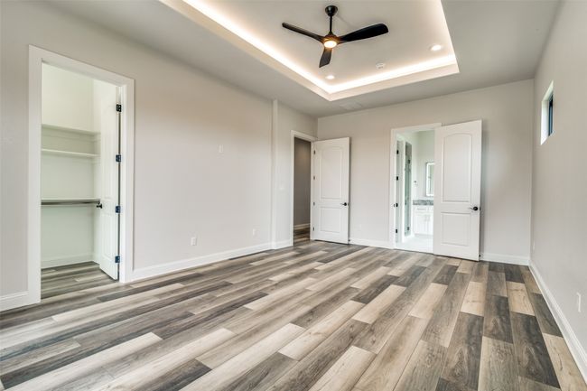 Unfurnished room with a tray ceiling, hardwood / wood-style flooring, and ceiling fan | Image 25