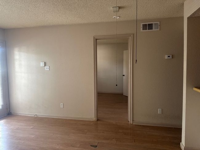 Empty room with a textured ceiling and light wood-type flooring | Image 4
