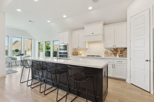 Kitchen with a sink, tasteful backsplash, light countertops, a kitchen bar, and recessed lighting | Image 7