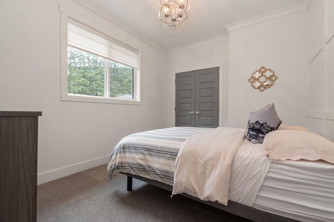 Carpeted bedroom featuring baseboards, an inviting chandelier, and ornamental molding | Image 22