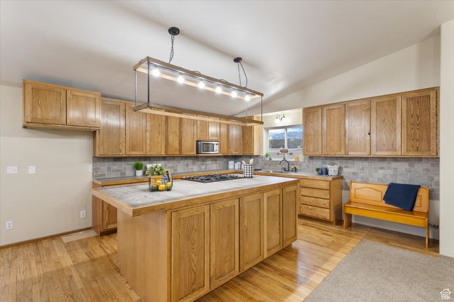 Kitchen with light wood-type flooring, backsplash, appliances with stainless steel finishes, and vaulted ceiling | Image 4