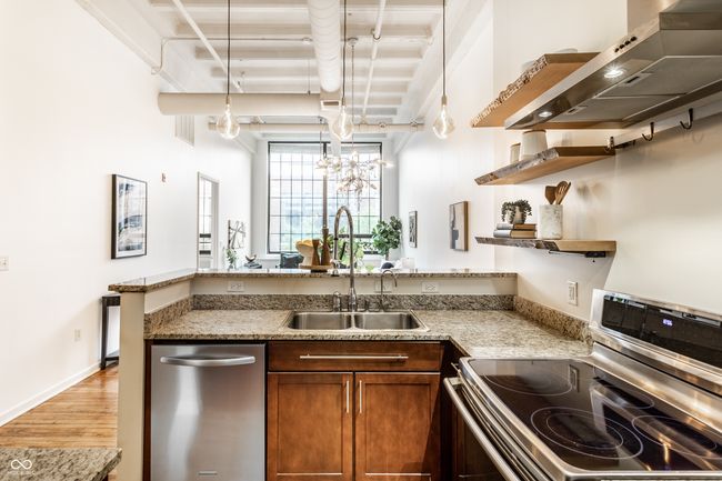 kitchen featuring stainless steel appliances, wall chimney exhaust hood, open shelves, a peninsula, and light wood finished floors | Image 18