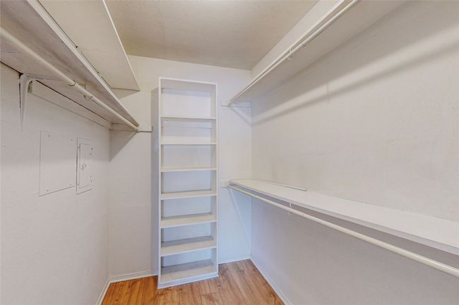 A bright walk-in closet with built-in shelves designed for storage and easy access. | Image 26