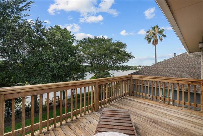 2nd story wooden deck with a view of lush greenery and the fountain in Kirby Lake, ideal for relaxing after a long day. | Image 25