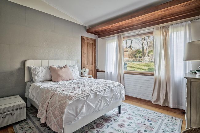Bedroom featuring wood finished floors, vaulted ceiling, and multiple windows | Image 9
