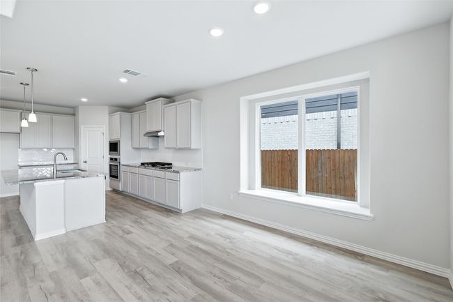 Kitchen with appliances with stainless steel finishes, light stone countertops, tasteful backsplash, light wood-style flooring, and pendant lighting | Image 10