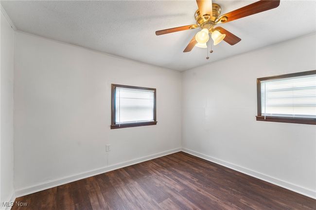 Empty room with healthy amount of natural light, dark wood-style floors, and ceiling fan | Image 15