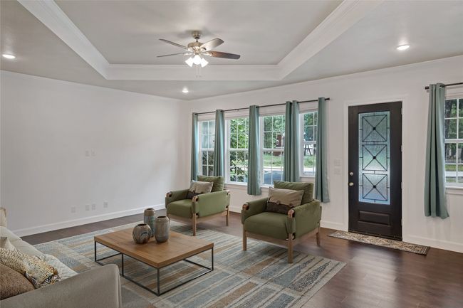 Living area with healthy amount of natural light, ceiling fan, dark wood finished floors, a raised ceiling, and recessed lighting | Image 7