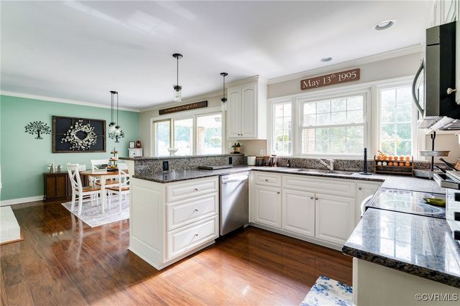This kitchen includes a pantry, granite countertops, beautiful laminate flooring and an eat-in area with fireplace | Image 6