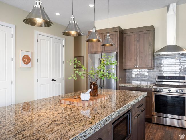 Kitchen with appliances with stainless steel finishes, wall chimney exhaust hood, tasteful backsplash, light stone countertops, and recessed lighting | Image 9