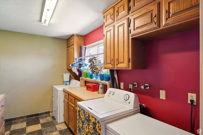Laundry area with cabinet space, washer and dryer, dark flooring, and baseboards | Image 9