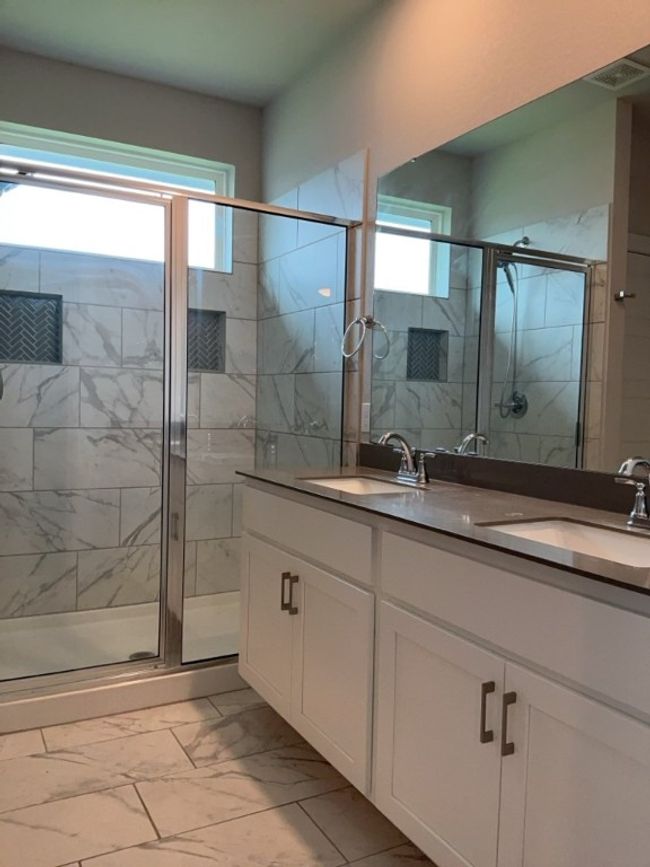 Full bath featuring marble look tile flooring, double vanity, and a stall shower | Image 19