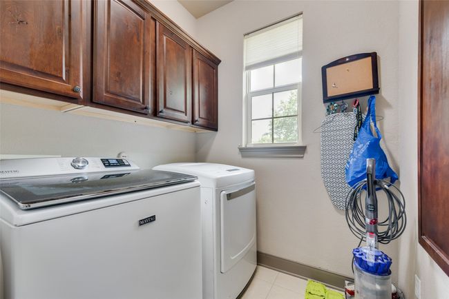 Washroom with cabinet space, washer and dryer, and light tile patterned flooring | Image 23
