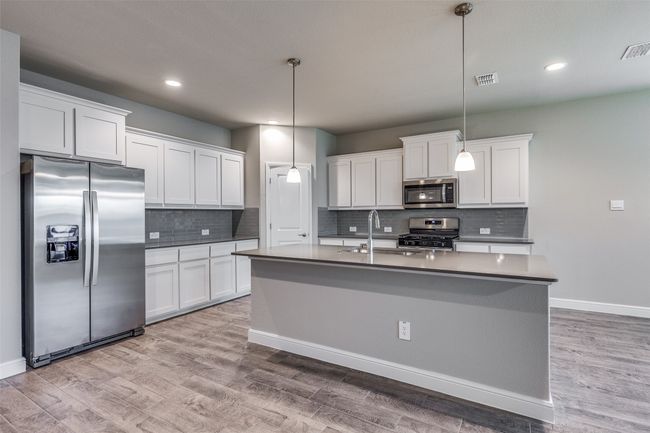Kitchen featuring stainless steel appliances, an island with sink, wood-type flooring, white cabinets, and sink | Image 6