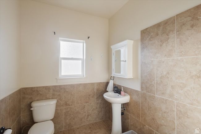 Bathroom featuring toilet, tile walls, and wainscoting | Image 26