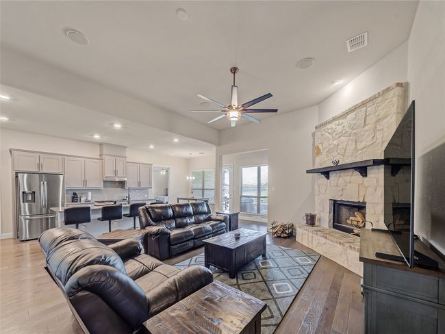 Living room featuring light wood finished floors, ceiling fan, recessed lighting, and a stone fireplace | Image 18