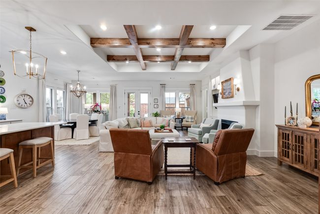 Living area featuring a chandelier, coffered ceiling, wood finished floors, beam ceiling, and a fireplace | Image 5