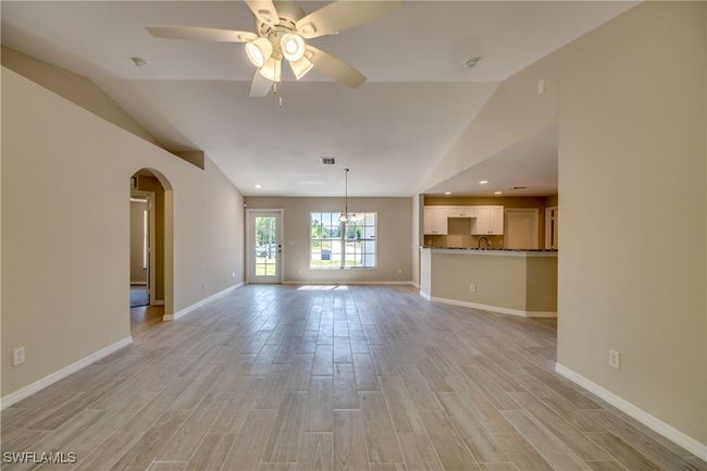 Unfurnished living room featuring light wood-type flooring, baseboards, arched walkways, and a ceiling fan | Image 19