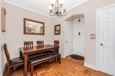 Dining space with light parquet floors and an inviting chandelier | Image 3