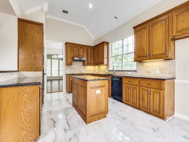 Kitchen with dishwasher, a center island, custom 42" cabinets, under cabinet range hood. New microwave and trim kit are on order. Some of the lower cabinets have pull out shelving. | Image 13