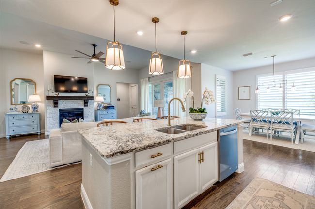 The open-concept layout allows the chef to stay connected with guests, overlooking both the living room and breakfast area. Thoughtful touches include a hidden trash and island sink. Gold hardware elevates the look of this space. | Image 10