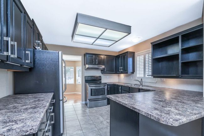 Kitchen featuring tasteful backsplash, under cabinet range hood, a sink, a peninsula, and appliances with stainless steel finishes | Image 15