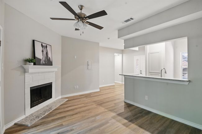 Unfurnished living room featuring light wood-style flooring, baseboards, visible vents, a fireplace with raised hearth, and a ceiling fan | Image 4