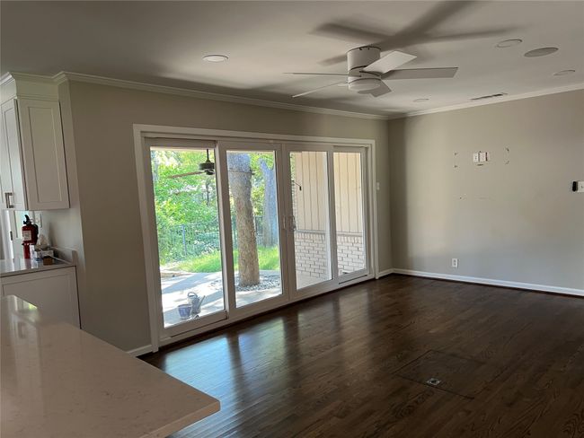 Unfurnished living room with dark wood-type flooring, ornamental molding, a ceiling fan, and recessed lighting | Image 10