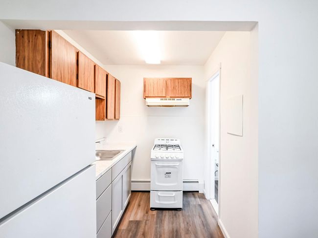 Kitchen featuring white appliances, a baseboard radiator, dark hardwood / wood-style floors, and sink | Image 18