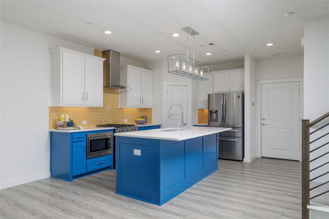 Kitchen featuring appliances with stainless steel finishes, wall chimney exhaust hood, light countertops, white cabinets, and recessed lighting | Image 8