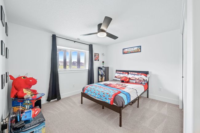 Bedroom with light colored carpet, baseboards, and a ceiling fan | Image 28