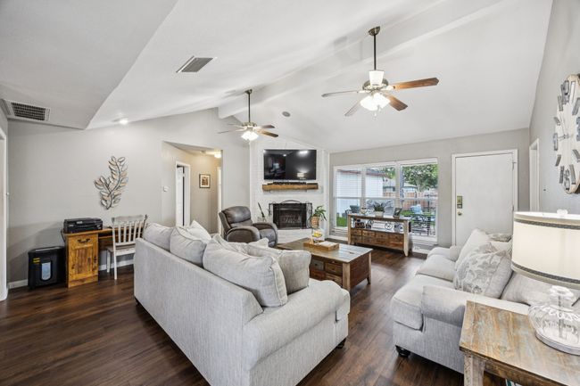 Living area with a brick fireplace in the corner and a vaulted ceiling | Image 4