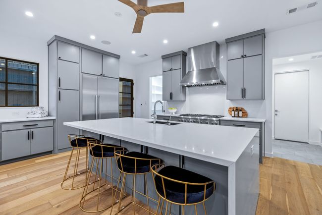 Kitchen featuring wall chimney range hood, gray cabinets, light wood-style flooring, ceiling fan, and recessed lighting | Image 8