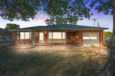 View of front of house with covered porch, a garage, and a lawn | Image 1