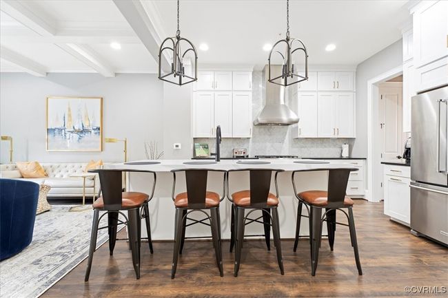 Kitchen with high end refrigerator, wall chimney exhaust hood, a notable chandelier, and tasteful backsplash | Image 14