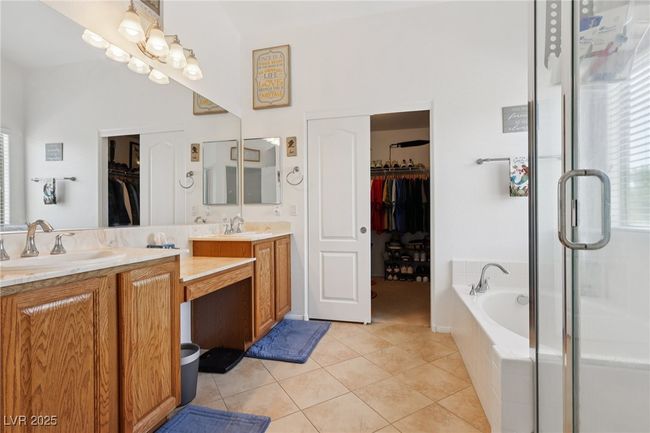 Full bathroom with double vanity, a spacious closet, tile patterned flooring, a bath, and a stall shower | Image 51