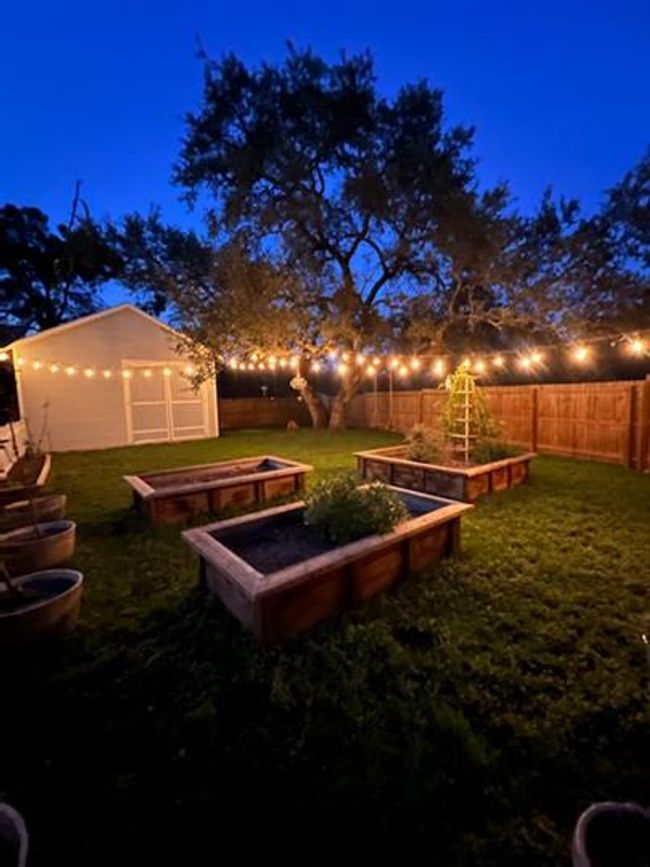 View of yard featuring a garden and string patio lights | Image 16
