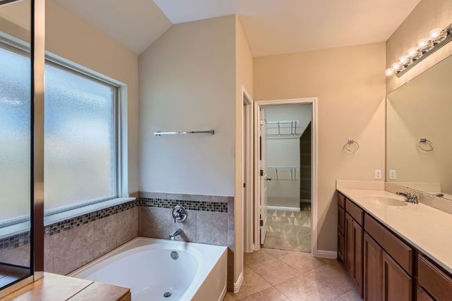 Primary Bathroom featuring vanity, a garden tub, a walk in closet, and tile patterned floors | Image 19