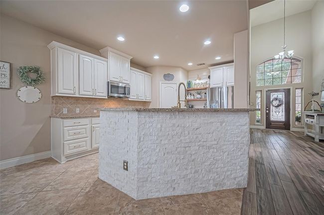 This custom breakfast bar showcases a stunning stacked stone surround and plenty of room for bar stools, creating a cozy spot to chat while remaining part of the kitchen’s action. | Image 15