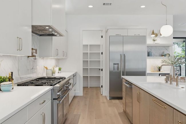 Kitchen with premium appliances, a sink, light wood-style flooring, light countertops, and tasteful backsplash | Image 7