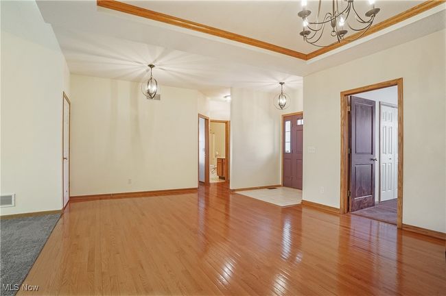 Unfurnished living room with light wood-type flooring, visible vents, and an inviting chandelier | Image 14