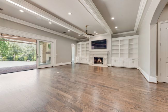 Unfurnished living room featuring baseboards, a ceiling fan, wood finished floors, and crown molding | Image 9
