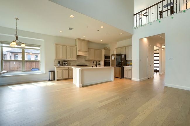 Kitchen with decorative backsplash, light wood-type flooring, cream cabinets, stainless steel appliances, and visible vents | Image 10